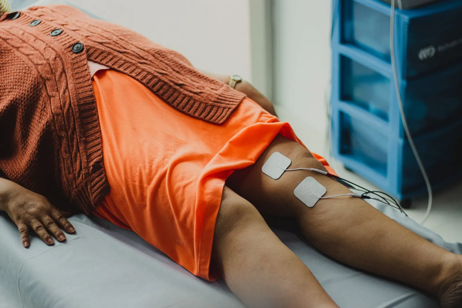 Patient lying on a treatment couch with electrotherapy pads on her thigh